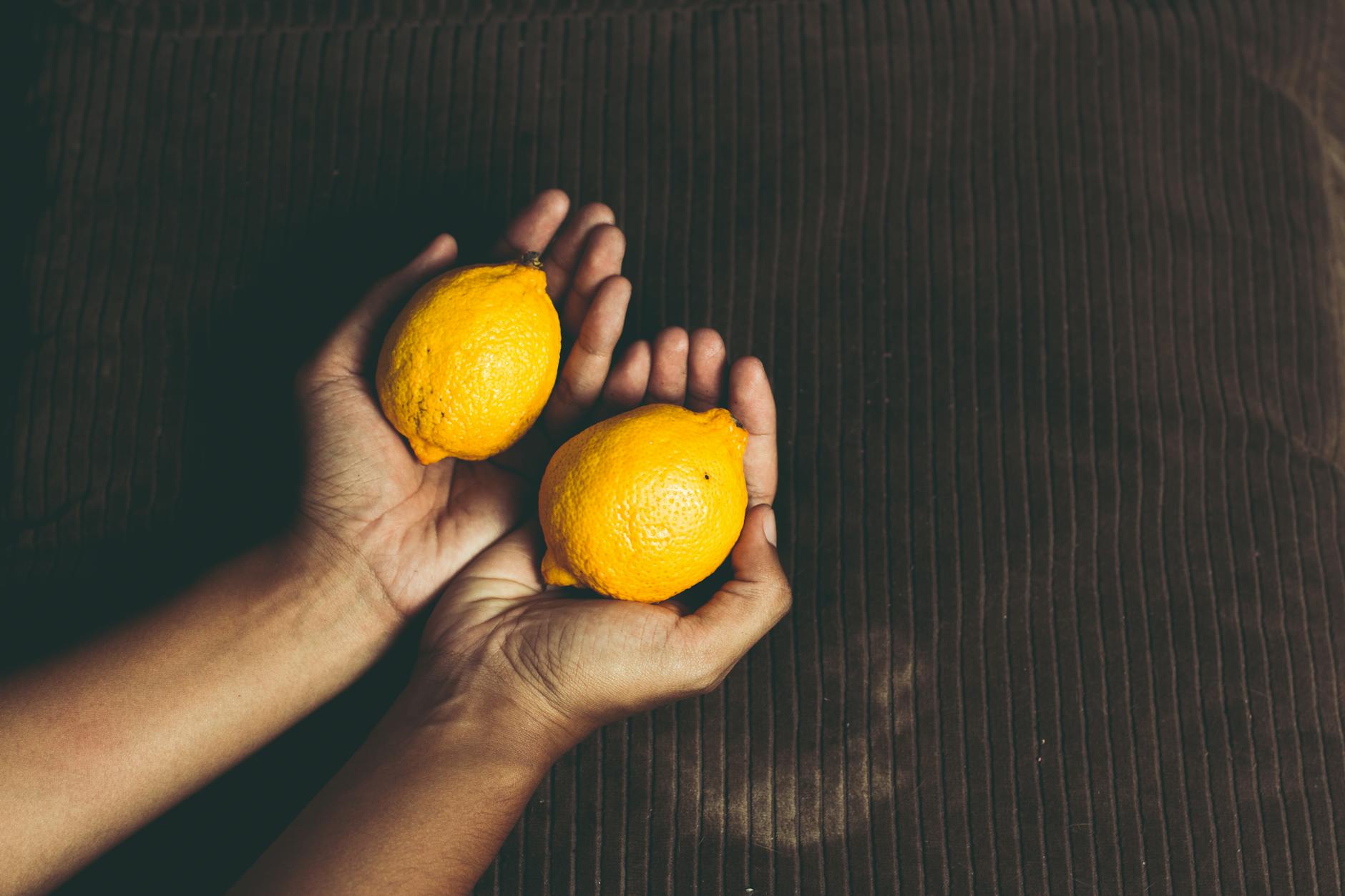 A hand holds a fresh lemon against a bright yellow background, symbolizing a fresh start and renewed connection