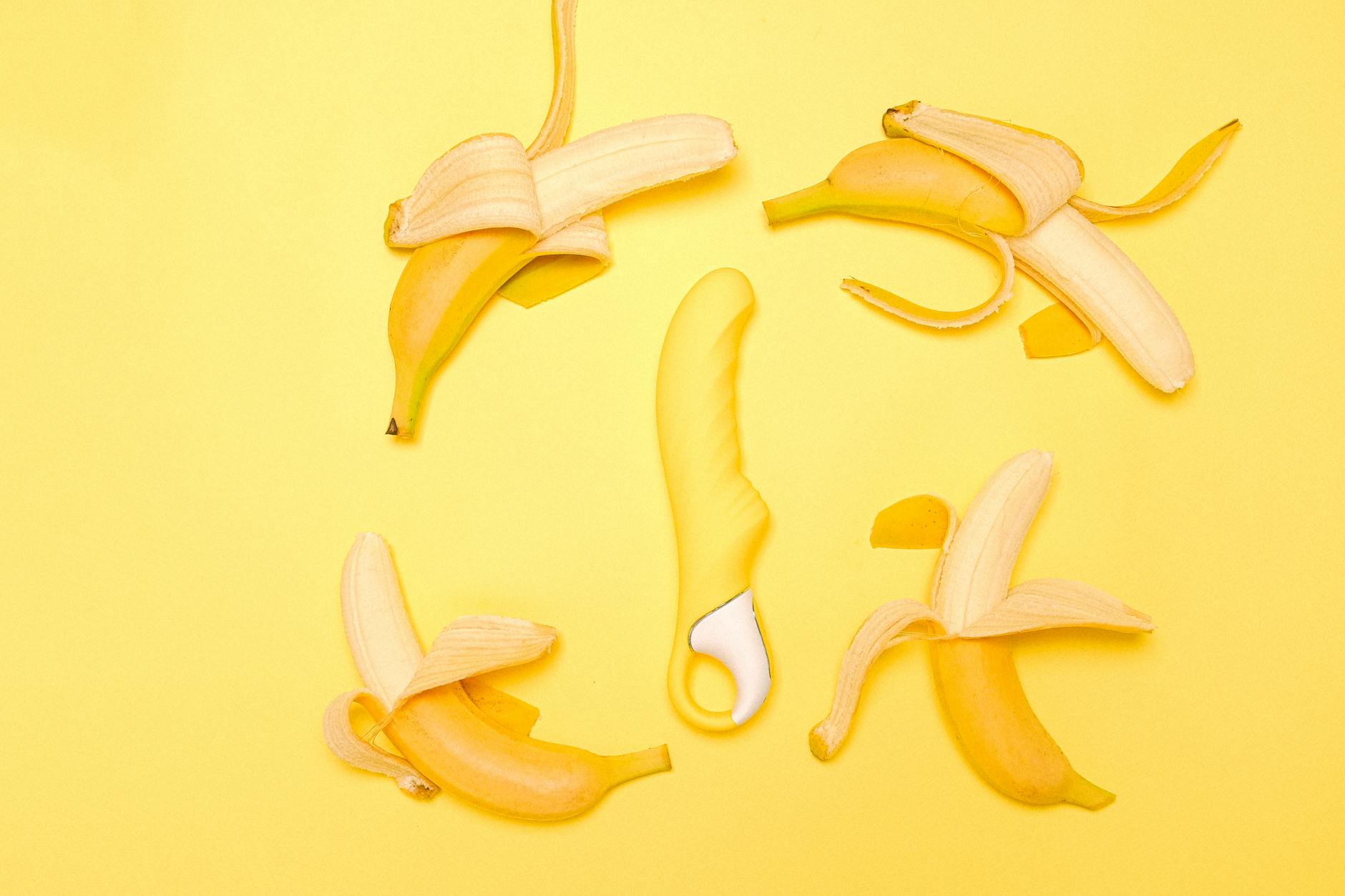 Bright yellow lemon vibrator arranged with fresh lemons on a soft yellow background