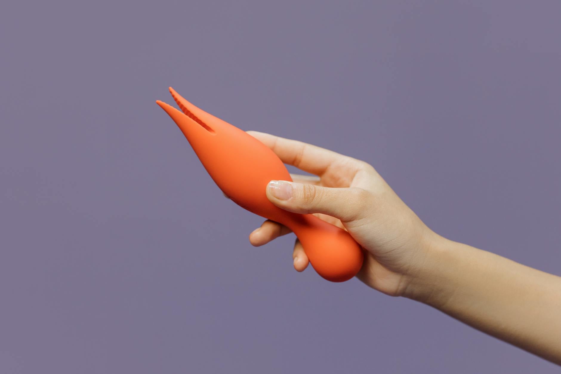 Hand holding a lemon-colored vibrator against a purple backdrop, representing modern couple intimacy