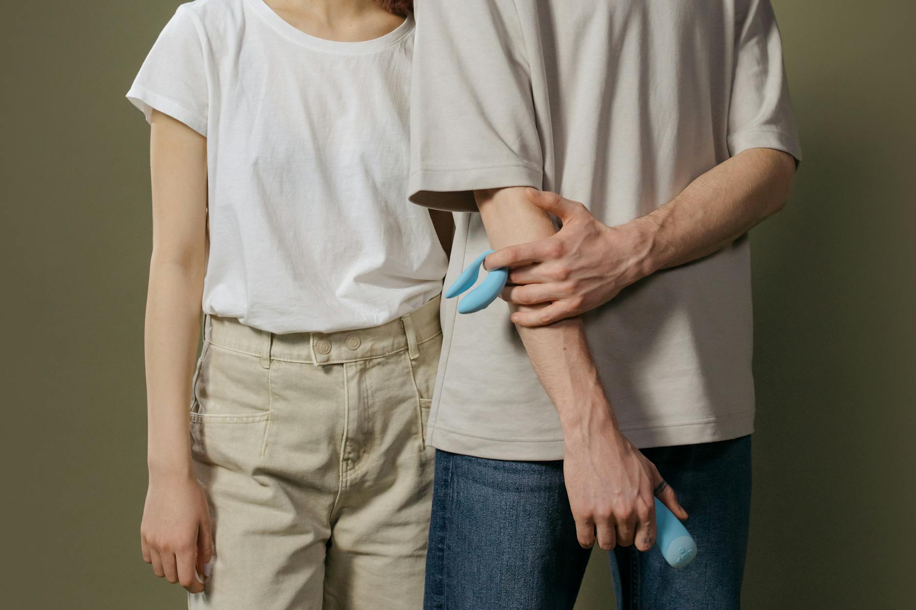 A couple holding a vibrator together indoors, symbolizing shared intimacy and presence.